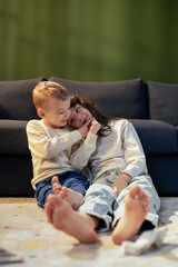Brother and sister embracing on carpet near sofa at home
