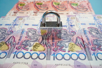 Metal lock and banknotes of Kazakhstani tenge 5000 and 10,000.