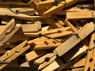 Clothespins beige wooden and plastic colorful clothespins lie in a pile under the sun rays taken from a close distance together with silver metal springs