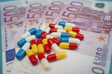 Euro banknotes and a handful of capsule tablets. Medicines. Medical expenses. Dependence.