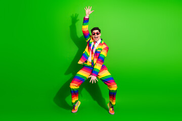Young man wearing a vibrant rainbow-striped suit expressing lively energy with funky poses against...