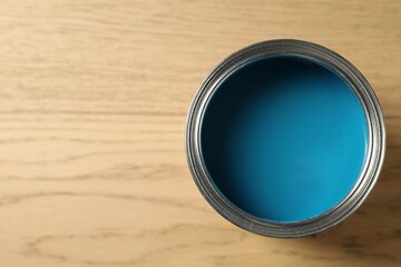 Can of light blue paint on wooden background, top view. Space for text