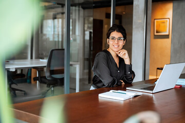 Smiling 30s latin hispanic middle-aged business woman working on laptop computer in modern office....