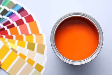Can of bright paint and color palettes on light grey background, flat lay