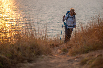 Fototapeta premium Senior woman is hiking outdoors, enjoying nature expression looks into the distance observing and possibly guide trekking and trail ecotourism adventure concept. 