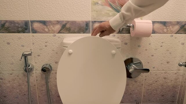 In the toilet, a man's hand presses the flush button on the toilet cistern, a strong stream of water flushes everything down the drain. Shot in motion. Closeup. Slow mo, slow motion, high speed camera
