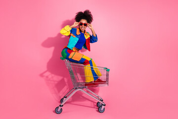 Vibrant young woman enjoying shopping with a playful style on a pink background