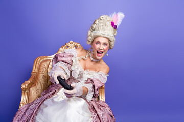 Elegant woman in baroque costume enjoying entertainment on a bright violet background