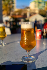 A refreshing glass of cold beer sits on an outdoor table, ready to be enjoyed in the sun.