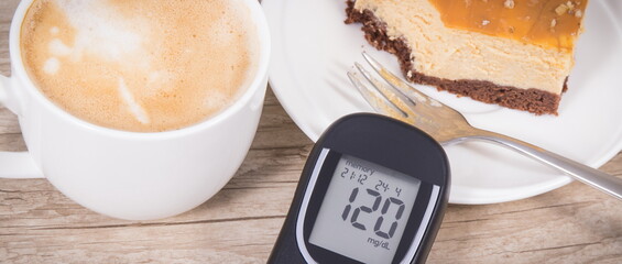 Glucometer, portion of cheesecake and cup of coffee with milk. Measuring and checking sugar level...