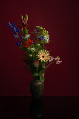 Bouquet of flowers in a vase on a burgundy red background