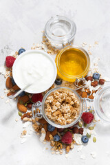 homemade granola with berries and nuts on white table, top view vertical