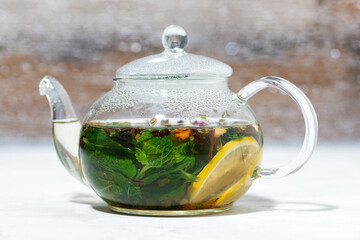 tea with fresh mint and lemon in a glass teapot