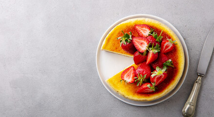 Cheesecake dessert with fresh strawberries on a plate. Grey background. Copy space. Top view.