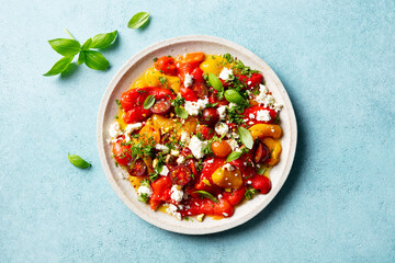 Bell pepper salad with cherry tomatoes and feta cheese. Blue background. Close up. Top view.