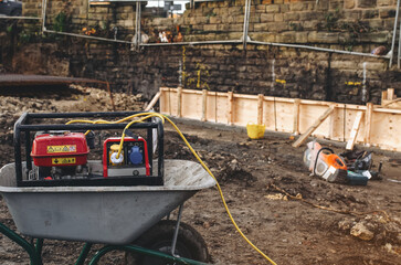 Fototapeta premium Construction site with wheelbarrow, generator, and power tools