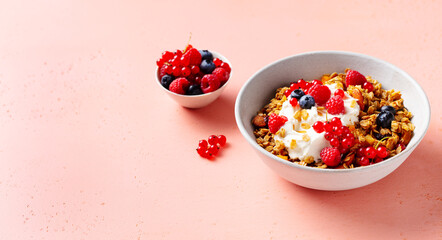 Healthy breakfast. Granola, muesli with yogurt and fresh berries. Pink background. Copy space. Close up.