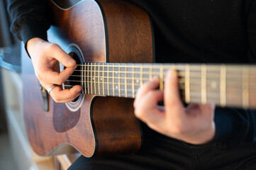 Fototapeta premium Skilled hands expertly play an acoustic guitar in beautiful natural light, showcasing artistry
