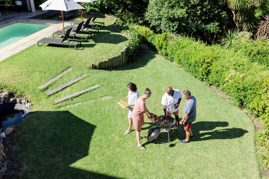 Grilling and socializing, Senior Friends having barbecue in sunny backyard together