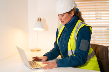 Female Construction worker engages in project planning while using a laptop in  office 