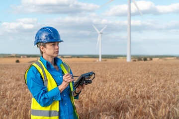 Young female engineer inspects wind farm
