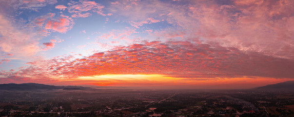 A breathtaking sunrise illuminates a small village nestled among lush green fields and karst...