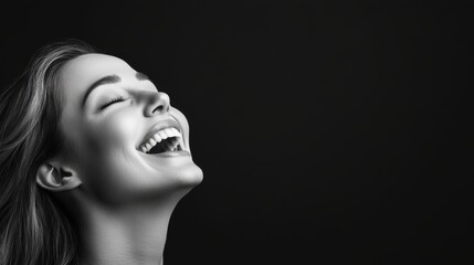 Fototapeta premium Joyful woman laughing with eyes closed against a dark background in striking black and white photography