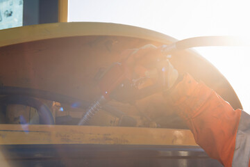 Worker handles fuel nozle equipment in bright sunlight at a construction site, demonstrating precise operation and safety procedures