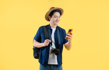 Portrait of young asian man traveling and using phone on yellow background © STOCK88PHOTOGRAPHER