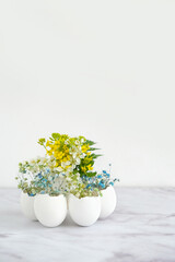 Beautiful composition with flowers in eggs shells on table, light background. symbol of spring...