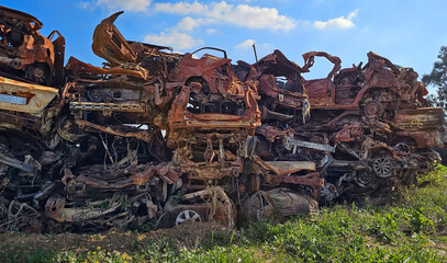 Damaged, broken, burnt and corroded cars in a scrapyard stacked up for recycling