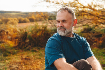 Man relaxing outdoors in autumn landscape, surrounded by colorful foliage and serene countryside...