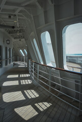 Fototapeta premium Outdoor promenade teak boat deck patio terrace onboard legendary ocean liner cruiseship cruise ship with close up of railing, deck chairs and life buoy 