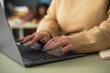 Close-up of businesswoman typing on laptop and working online at her workplace in office