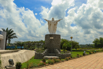 Statue of Christ overlooking serene landscape in Abidjan, Ivory Coast under blue sky