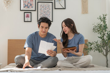 Asian Couple reviewing bills feels stressed having financial problem, check finances, experiencing lack of money pay for loan, huge taxes, utility rates, get eviction notice