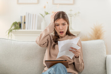 Asian woman reviewing bills feels stressed having financial problem, check finances, experiencing lack of money pay for loan, huge taxes, utility rates, get eviction notice