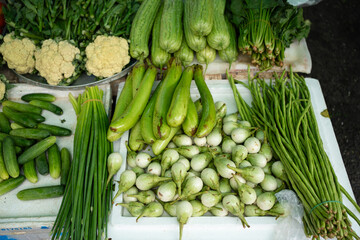 Fresh vegetables neatly arranged in the market. Long beans, shallots, cucumbers, bitter melon, cauliflower, brinjal, eggplants, and etc.