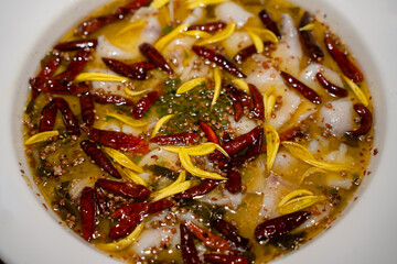 Sichuan Fish (Suan Cai Yu) close up serve in white bowl. Sichuan Fish (Suan Cai Yu) is cooked with fish fillet, dried chilies, Sichuan peppercorns, and pickled cabbage in Sichuan style.