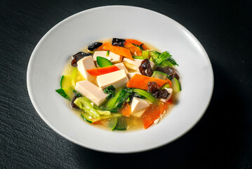 Tofu with traditional Chinese vegetables served on a dark background 