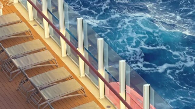 Sun loungers on cruise ship deck at sunset with waves passing by