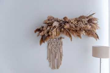 Pampas grass and macrame wall decor adding a touch of bohemian style to a minimalist interior,...