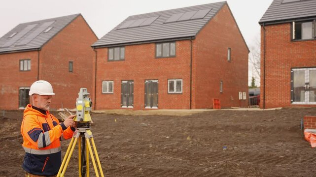 Construction worker using surveying equipment at new housing development site