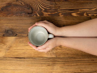 Hand Holds Cup, Empty Cup in Hands, Coffee Mug, Teacup Mockup, Cup in Arms on Wooden Table