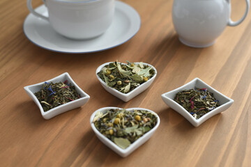 Tea time porcelaine cup and tea leaves in little bowls on wooden table