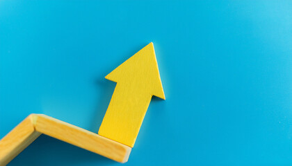 Yellow wooden arrow pointing upwards on blue background. Business and market growth concept