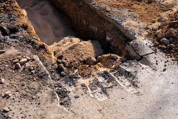 Construction site showing a trench being dug for utility installation on a sunny day