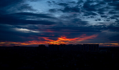City skyline at twilight with dramatic sunset and dark clouds. Urban landscape with high-rise buildings silhouetted against the colorful evening sky.