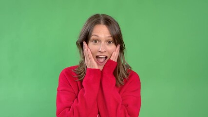 Excited young woman expressing joy and surprise in front of a green screen background during a creative photo session