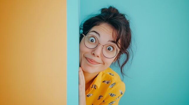 Curious young woman peeking around a corner with funny expression